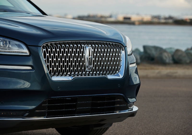 The Grand Touring grille shows floating chrome ovals that catch the glowing light of a theatre marquee and frame the distinctive Lincoln star