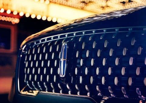 The Corsair Grand Touring grille shows floating chrome ovals that catch the glowing light of a theater marquee and frame the distinctive Lincoln Star | Covert Lincoln Austin in Austin TX