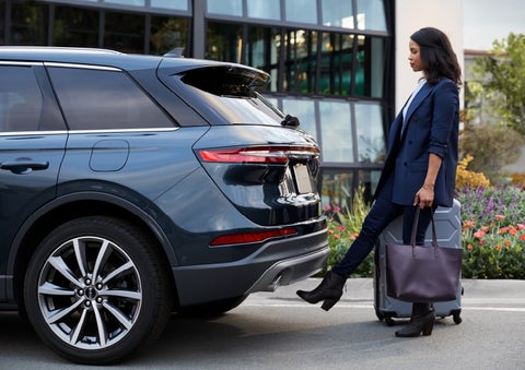 A woman with luggage and a bag opens the available hands-free liftgate by kicking her foot under the bumper | Covert Lincoln Austin in Austin TX