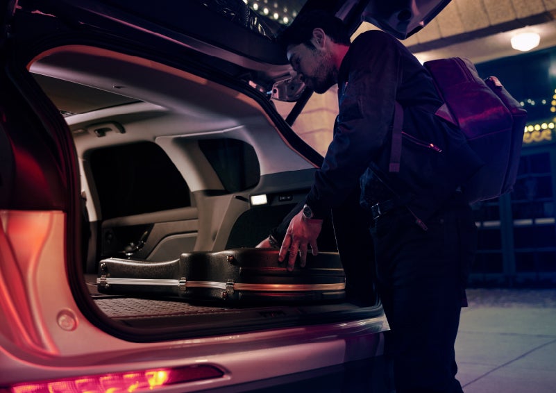 A musician slides his guitar case into the cargo space of a 2022 Lincoln Corsair with the rear seats folded flat to provide ample cargo space | Covert Lincoln Austin in Austin TX