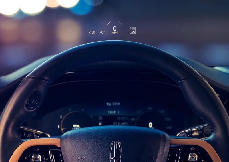 The available head-up display projects data on the windshield above the steering wheel inside a 2022 Lincoln Corsair as the driver navigates the city at night | Covert Lincoln Austin in Austin TX