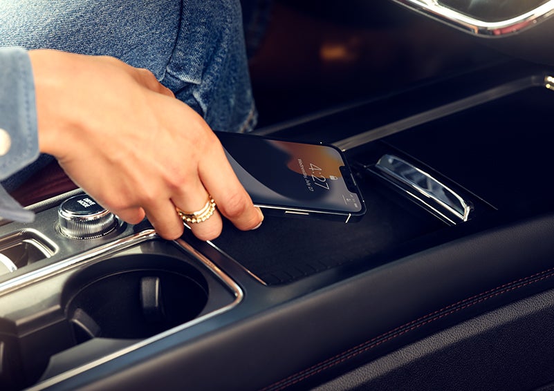 A smartphone is is being placed on the wireless charging pad in the front center console cubby. | Covert Lincoln Austin in Austin TX
