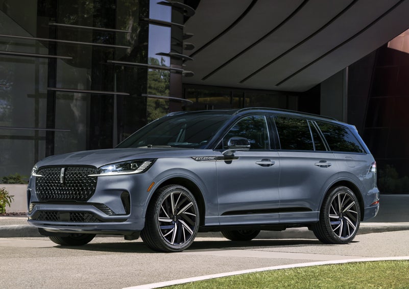 A gray 2025 Lincoln Aviator® SUV is parked outside a modern building showcasing the driver’s side of the vehicle. | Covert Lincoln Austin in Austin TX