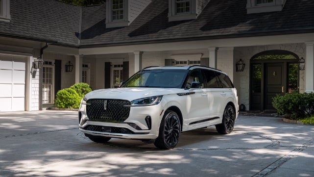 A white 2026 Lincoln Aviator® SUV is parked in the driveway of a luxury home. | Covert Lincoln Austin in Austin TX