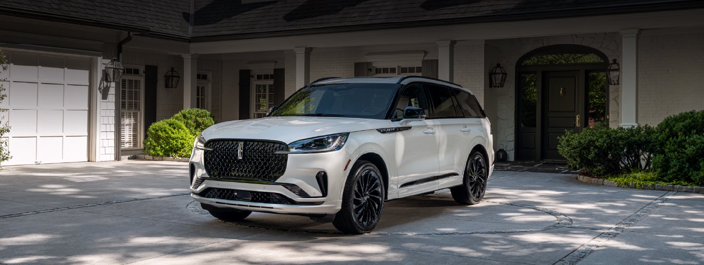 A white 2026 Lincoln Aviator® SUV is parked in the driveway of a luxury home. | Covert Lincoln Austin in Austin TX