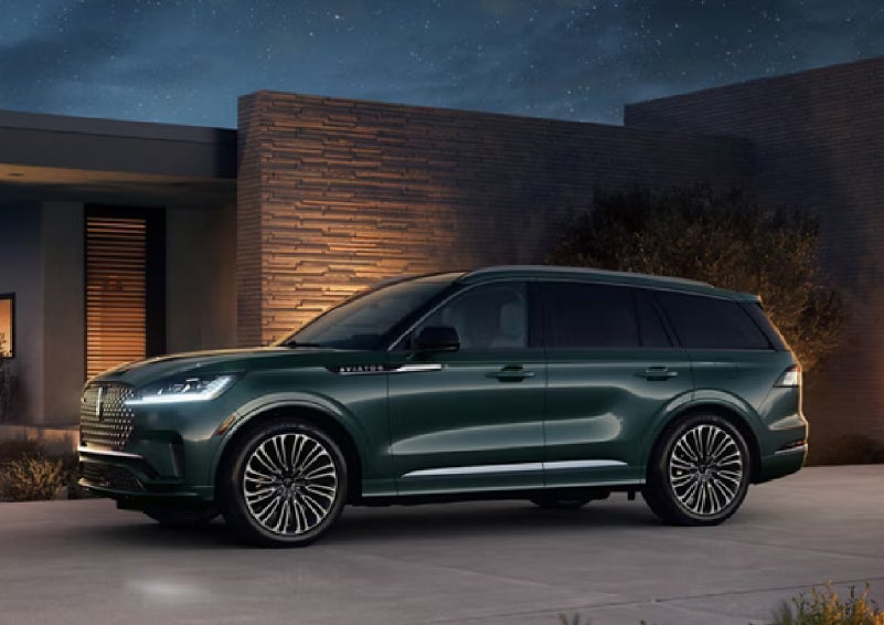 A green 2027 Lincoln Aviator® SUV is parked outside a contemporary home. | Covert Lincoln Austin in Austin TX