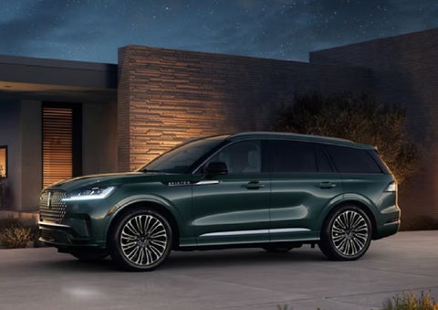 A green 2027 Lincoln Aviator® SUV is parked outside a contemporary home. | Covert Lincoln Austin in Austin TX
