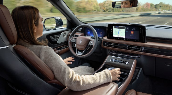 A 2027 Lincoln Aviator® SUV is being driven hands-free on a highway lined with trees. | Covert Lincoln Austin in Austin TX