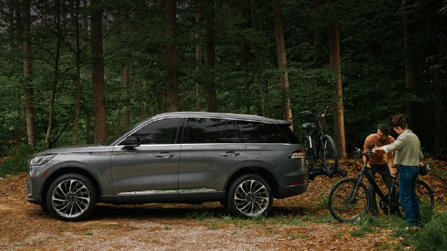 A father and son load e-bikes on a bike rack attached to a 2027 Lincoln Aviator® SUV. | Covert Lincoln Austin in Austin TX