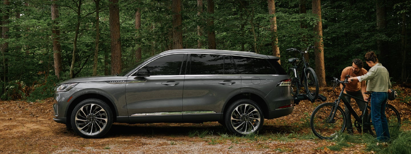 A father and son load e-bikes on a bike rack attached to a 2027 Lincoln Aviator® SUV. | Covert Lincoln Austin in Austin TX