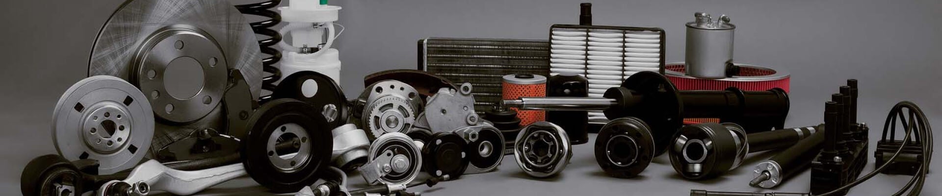 A lineup of various auto parts on a blank gray backdrop.