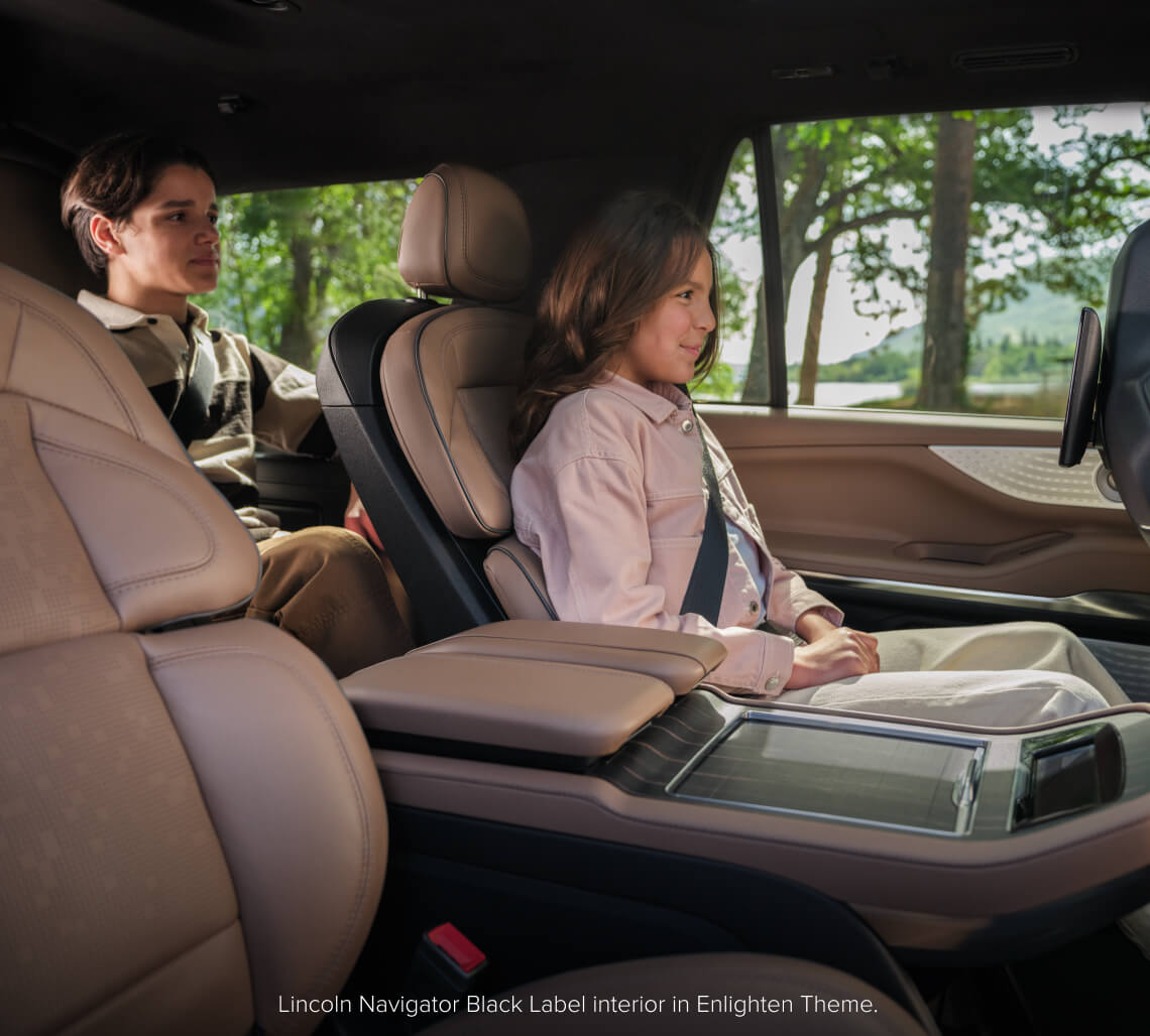 Interior passenger view of a Lincoln Navigator Black Label in Enlighten Theme with two children in the rear seats.